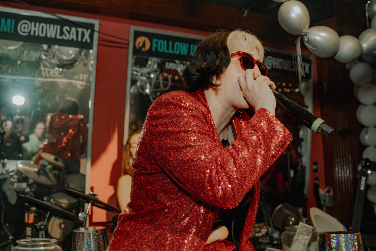 Female wearing a sparkly red jacket singing on stage at a holiday party