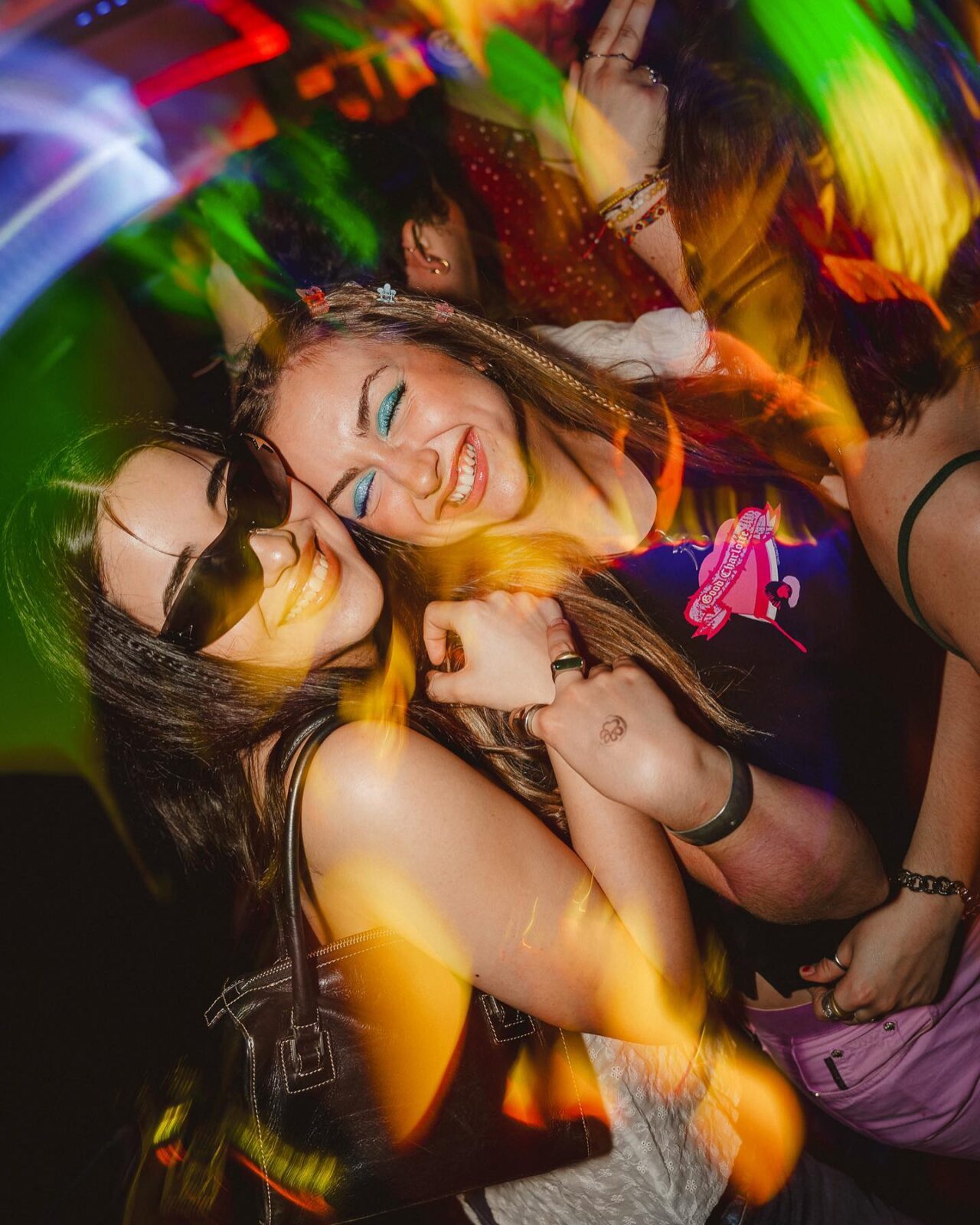 Friends dancing under colorful lights at a 2000’s Throwback Party, wearing Y2K-inspired outfits and sunglasses.