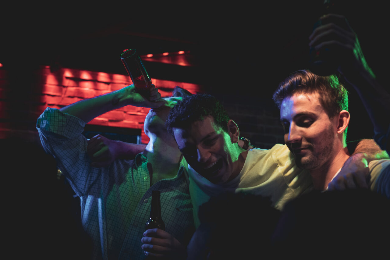 Three friends singing and raising drinks at a Dad Rock Music Party featuring live classic rock and divorced dad rock music vibes. Dad Rock Music Party.