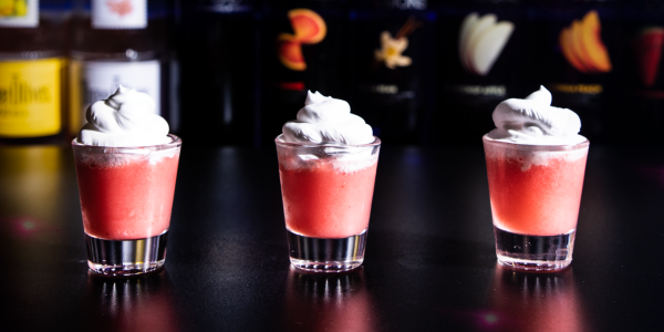 Strawberry shortcake shot topped with whipped cream held in hand at a 2000’s Party nightlife event.