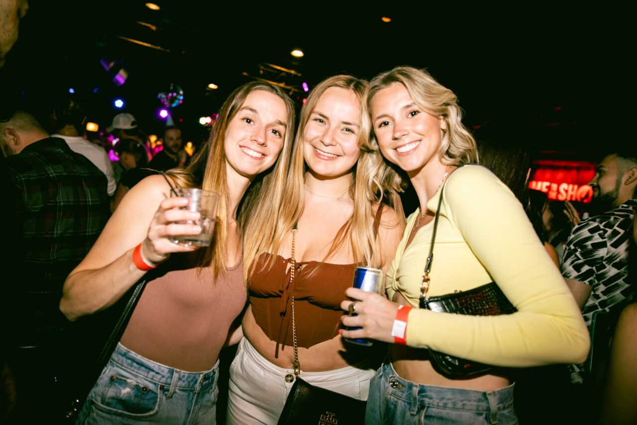 Group of friends smiling and holding drinks at Howl at the Moon during a Cinco de Mayo party night. Cinco de Mayo Specials