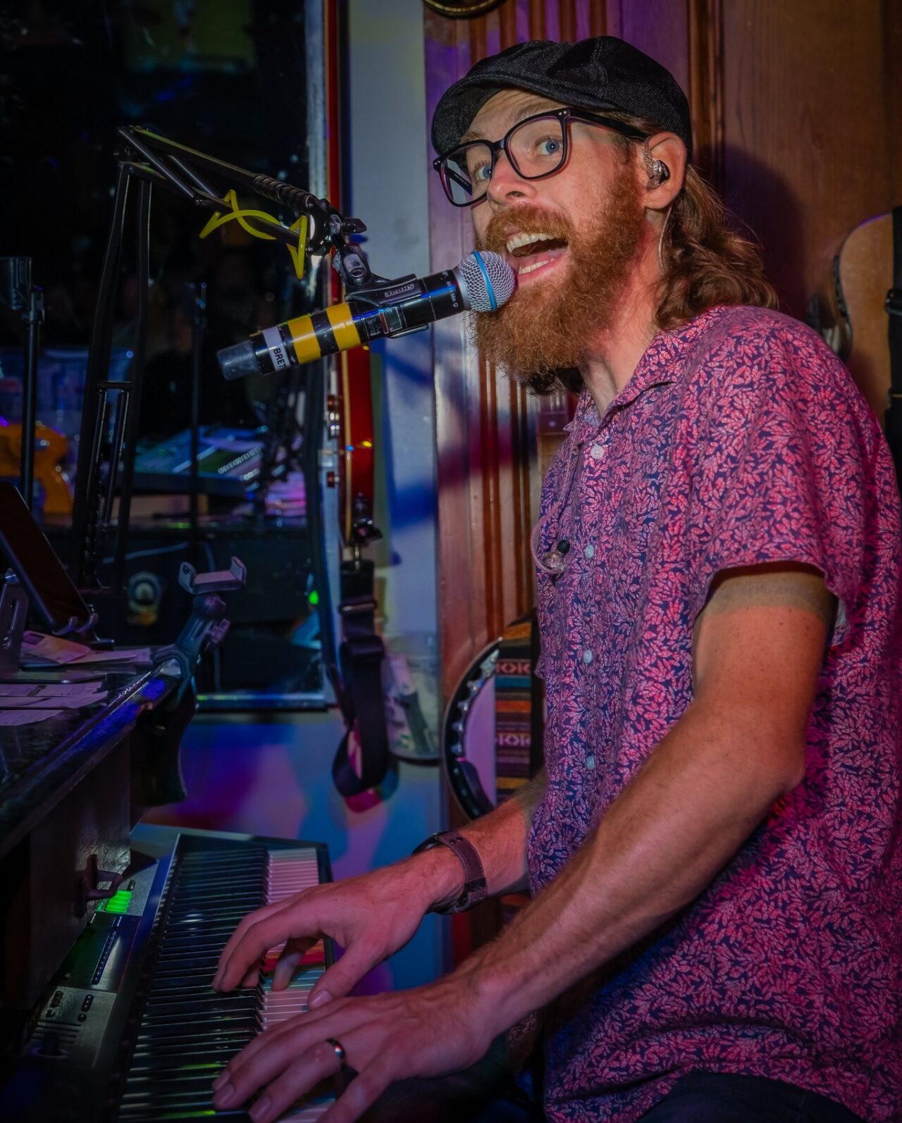 Live dueling piano musician performing at Howl at the Moon Louisville during Derby weekend, singing into a microphone while playing keyboard at the high-energy live music bar.