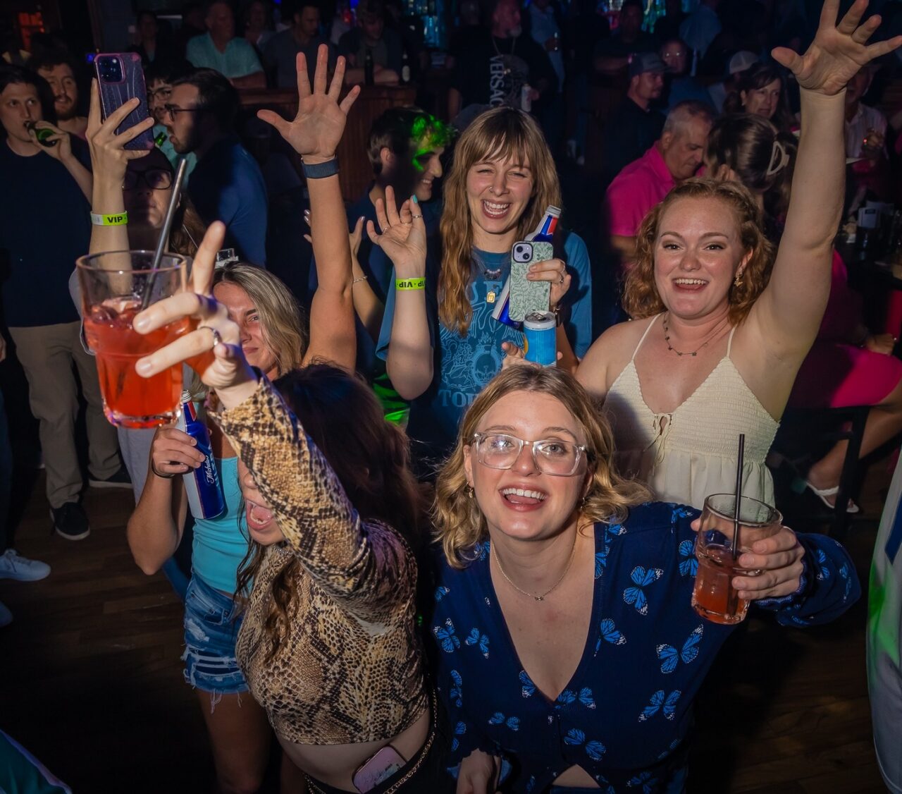 Friends raising drinks and cheering on the dance floor at Howl at the Moon Louisville during a lively night of live music and nightlife entertainment.
