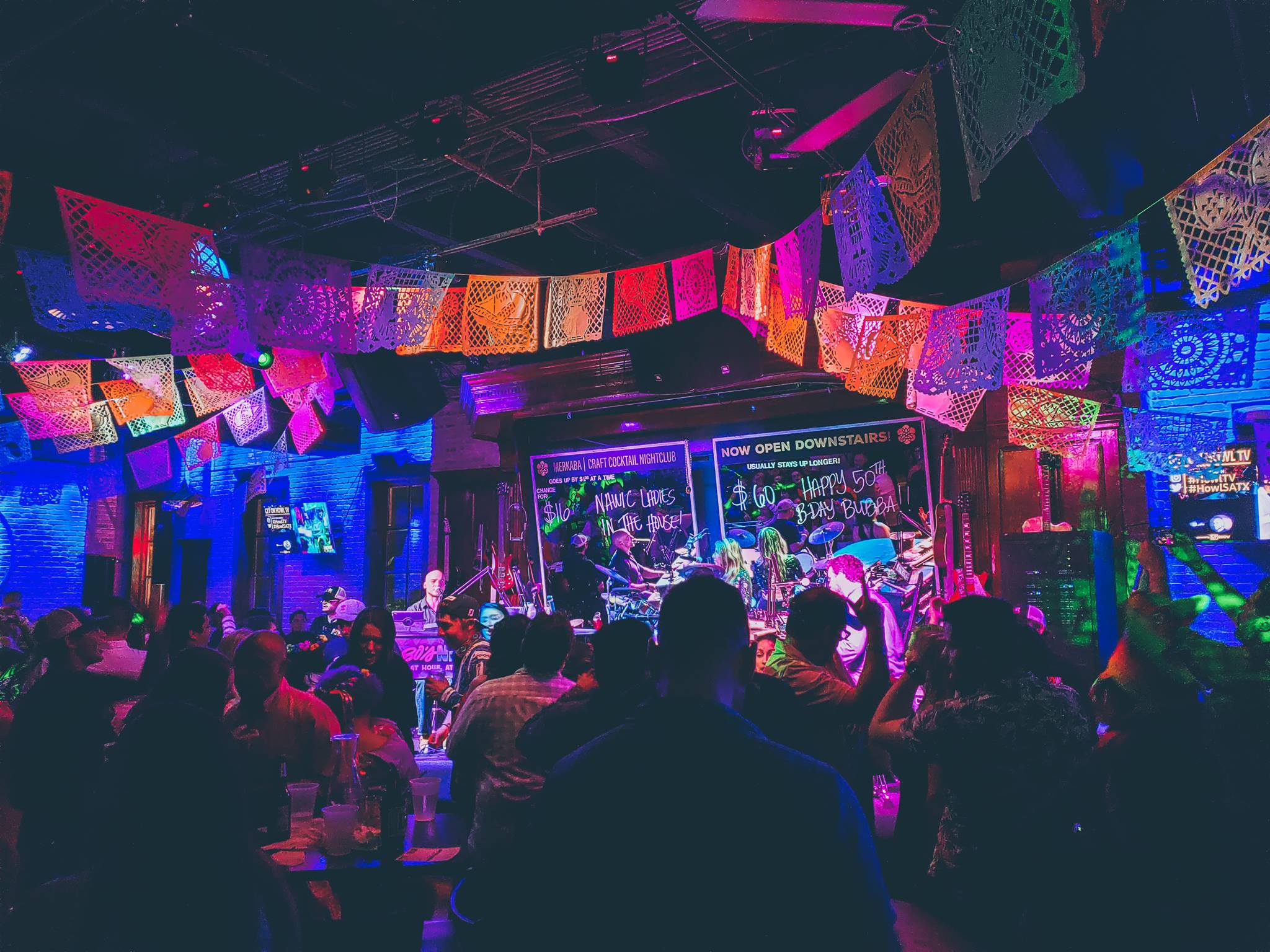 Crowded nightclub at Howl at the Moon decorated with colorful Cinco de Mayo banners and live band performing on stage. Cinco de Mayo Specials