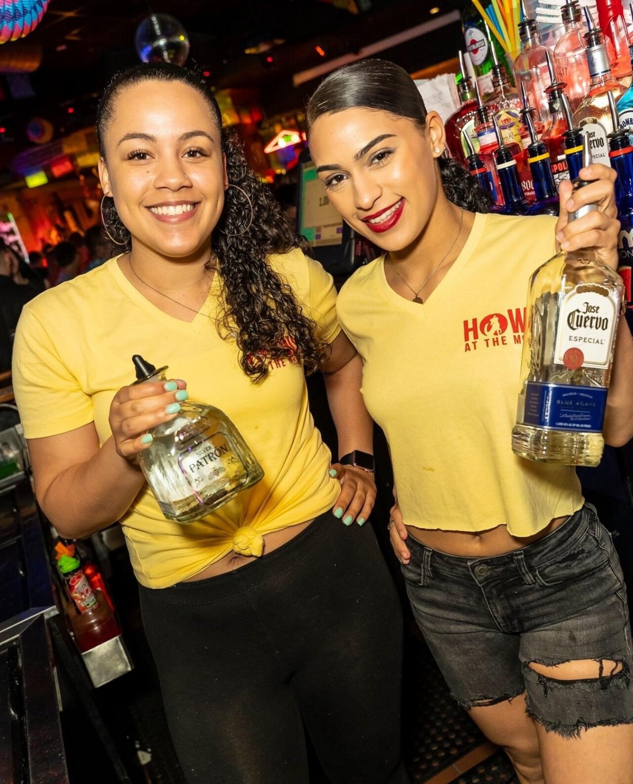 Bartenders at Howl at the Moon holding tequila bottles and smiling during Cinco de Mayo drink specials. Cinco de Mayo Specials.