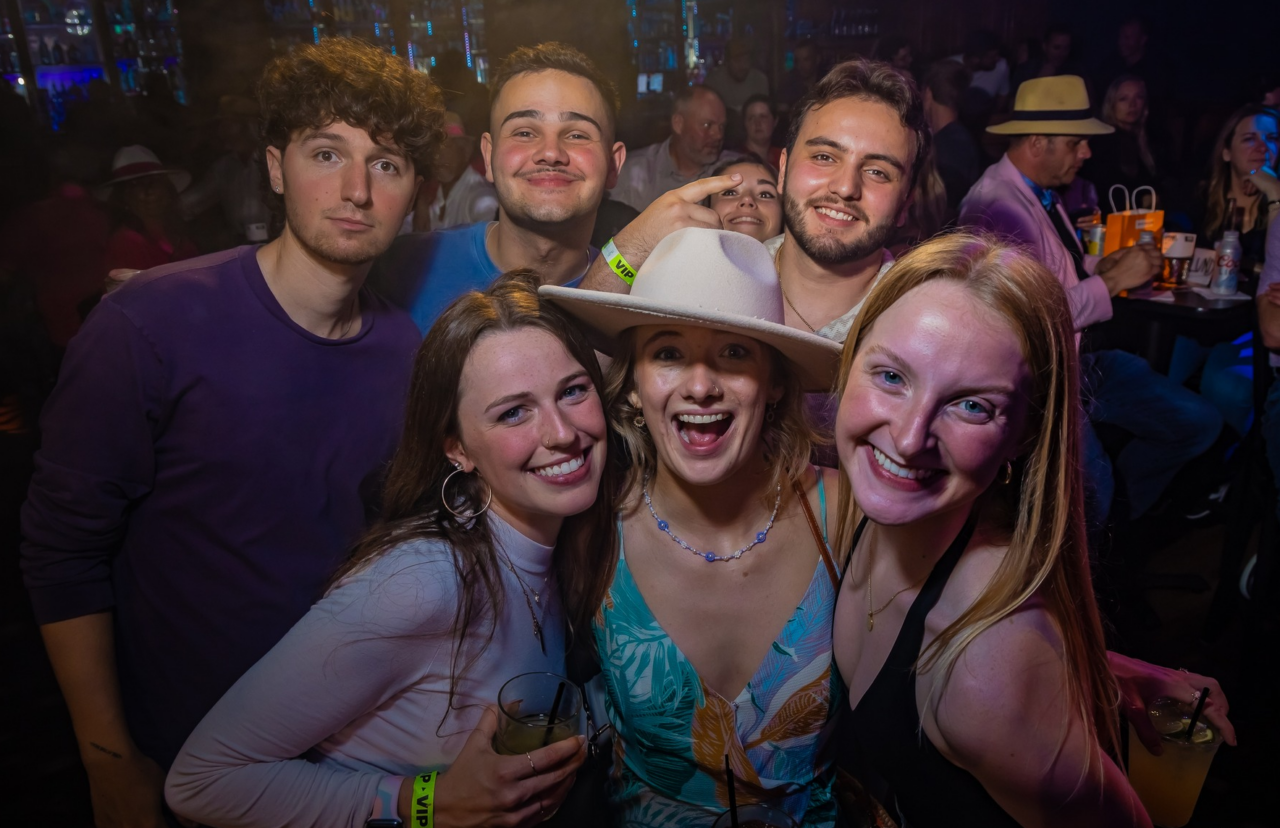 Friends smiling and dancing during the Louisville Kentucky Derby party at Howl at the Moon with drinks and a lively Derby weekend nightlife crowd.