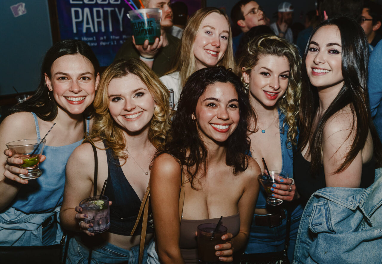 Friends celebrating together with bucket drinks during Happy Hour at Howl at the Moon.