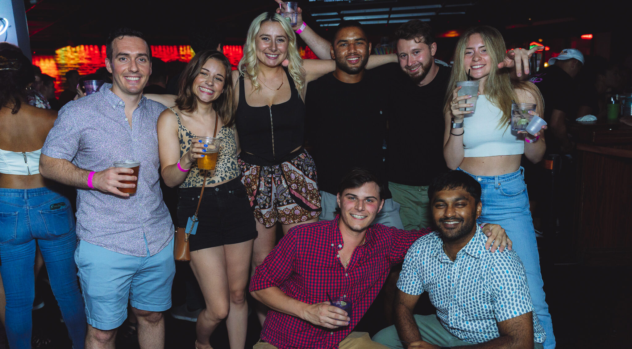 Group of friends posing together with drinks during a Happy Hour celebration at Howl at the Moon.