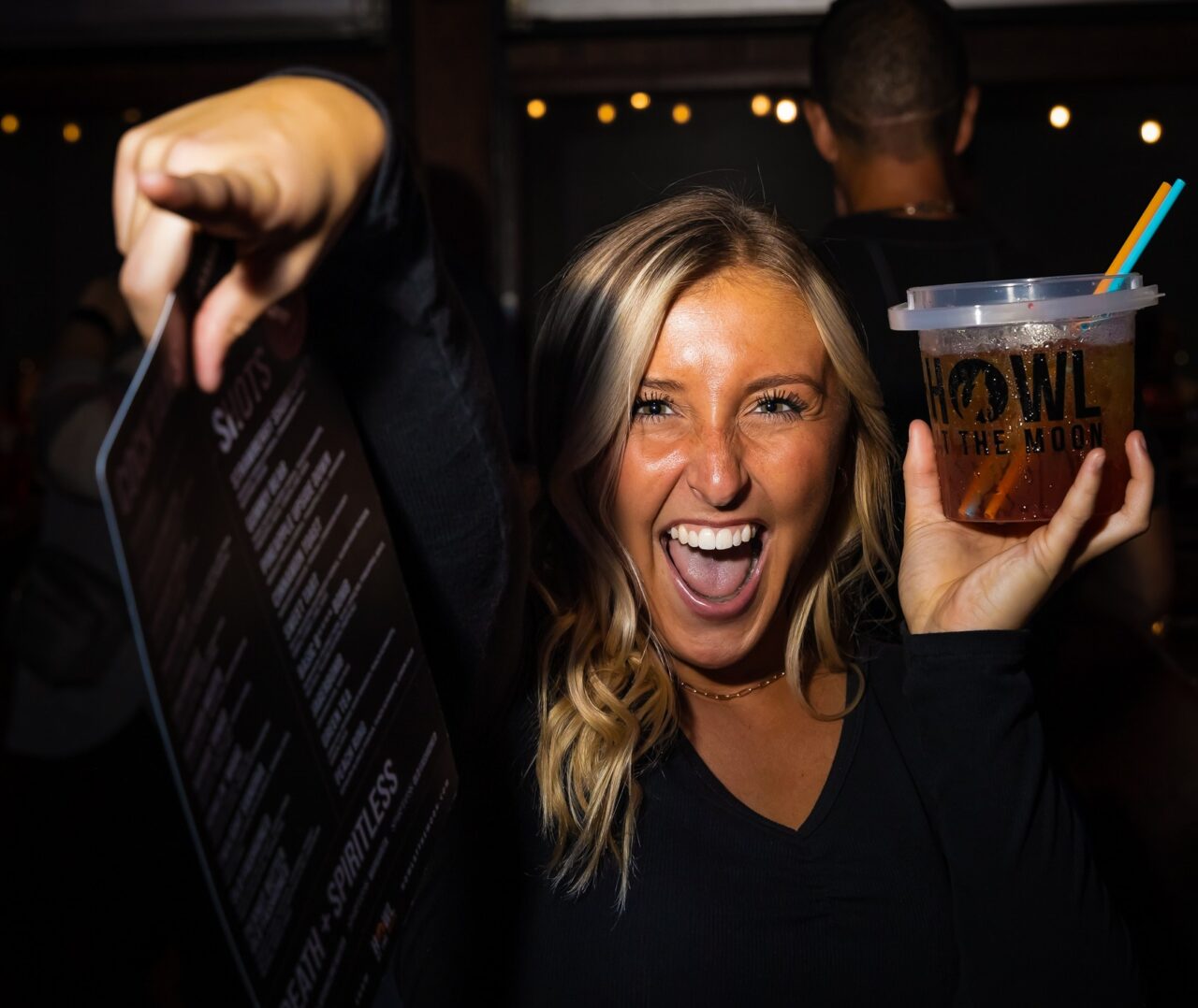 Woman celebrating with a signature bucket drink during Chicago Happy Hour at Howl at the Moon.
