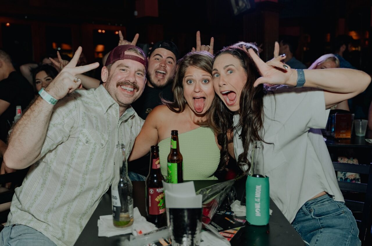 Friends posing with drinks during San Antonio Happy Hour at Howl at the Moon.