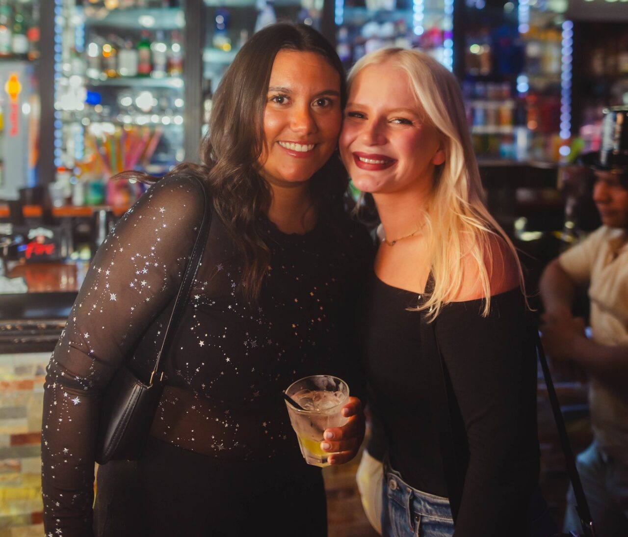 Two friends posing with drinks during Indianapolis Happy Hour at Howl at the Moon.
