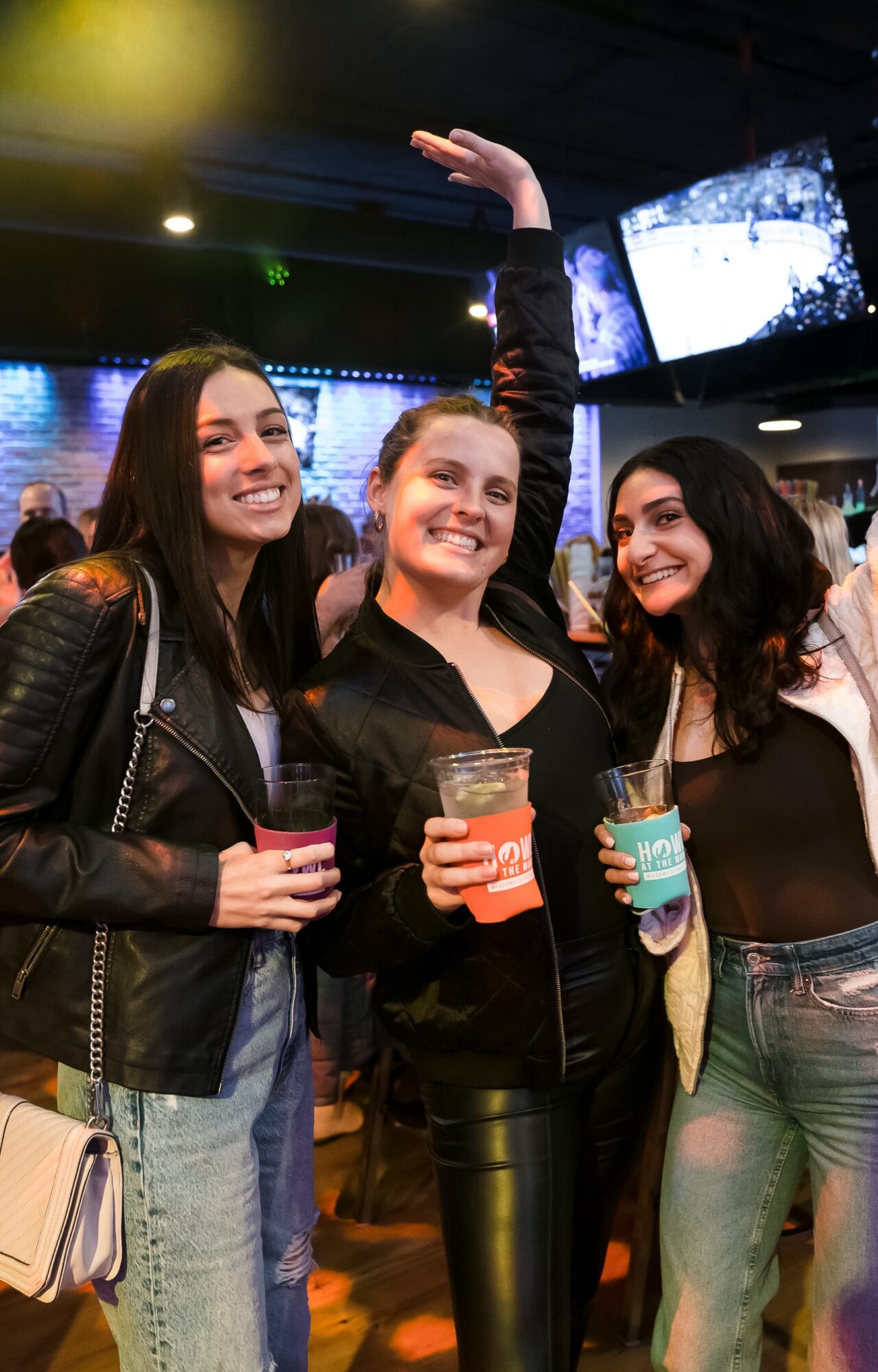 Friends holding drinks and smiling during the Boston Win a Party promotion at Howl at the Moon.